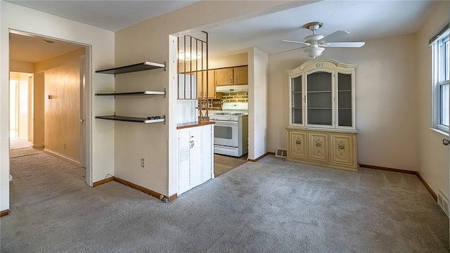 kitchen featuring light brown cabinetry, light colored carpet, white gas range, and ceiling fan