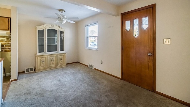 entryway featuring beamed ceiling, ceiling fan, and carpet floors