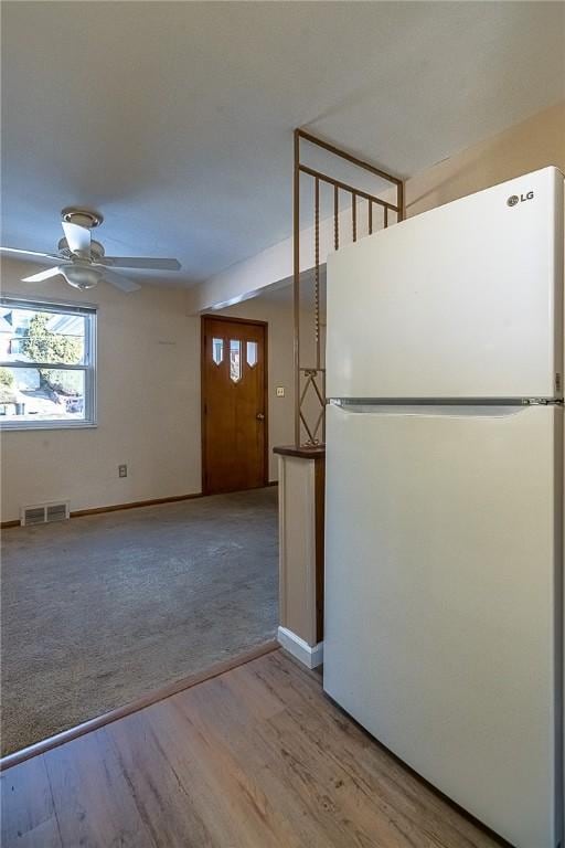 interior space with ceiling fan, white fridge, and wood-type flooring