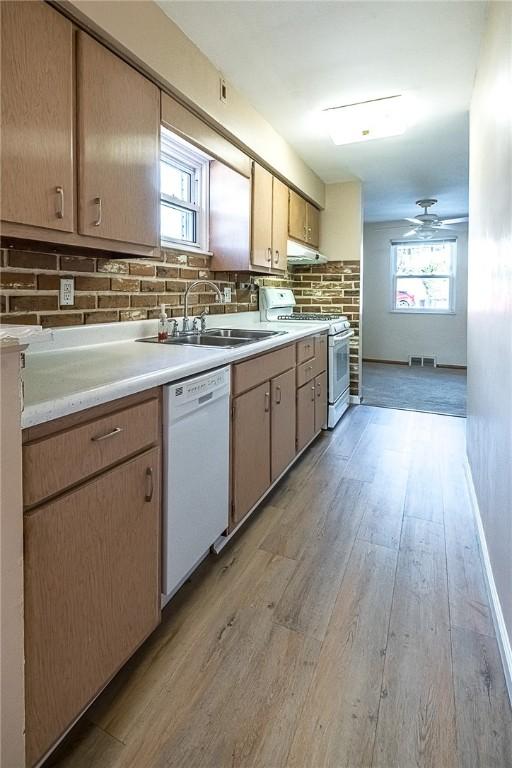 kitchen with white appliances, backsplash, sink, light hardwood / wood-style flooring, and ceiling fan