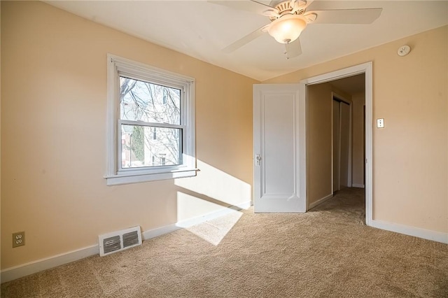 empty room with ceiling fan and light carpet