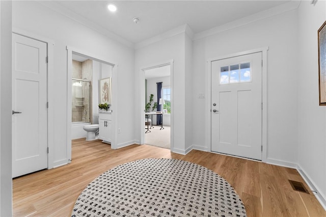 entrance foyer featuring crown molding and light hardwood / wood-style floors