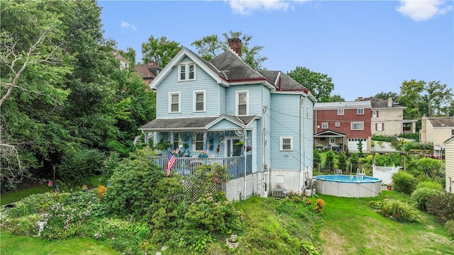 rear view of property with a fenced in pool, a yard, and central air condition unit