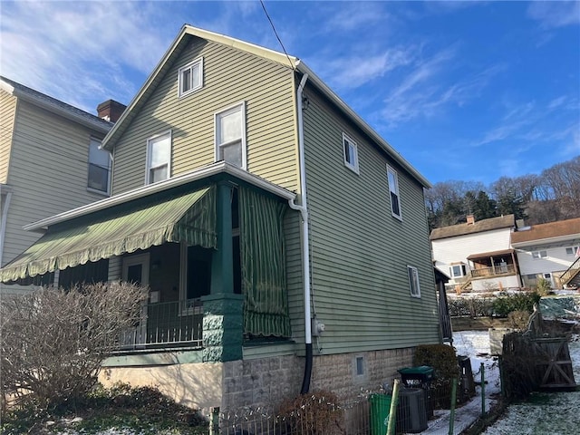 view of side of property featuring a porch and cooling unit