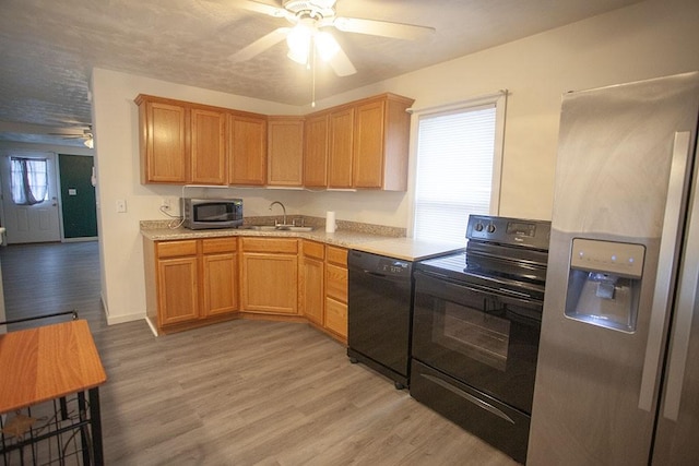 kitchen featuring sink, light wood-type flooring, plenty of natural light, and black appliances