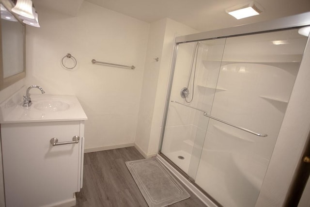 bathroom with wood-type flooring, vanity, and a shower with door