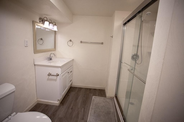 bathroom featuring vanity, wood-type flooring, a shower with shower door, and toilet