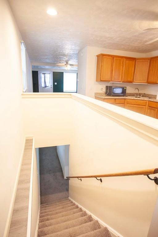 stairway featuring sink, a textured ceiling, and hardwood / wood-style flooring