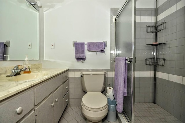 bathroom with vanity, tile walls, tile patterned flooring, toilet, and a shower with shower door