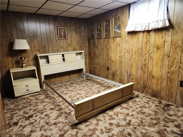 sitting room featuring carpet floors, a drop ceiling, and wood walls