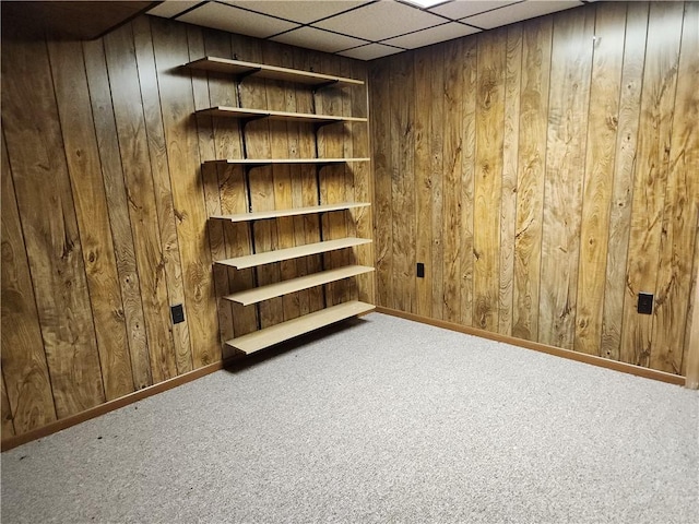 interior space featuring wood walls, a drop ceiling, and carpet floors