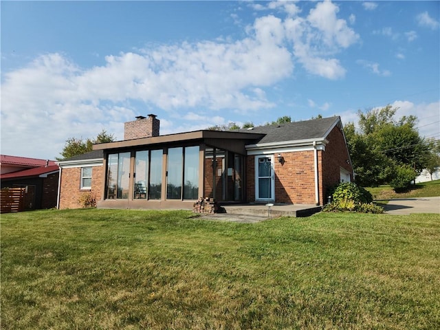 rear view of house with a lawn and a sunroom