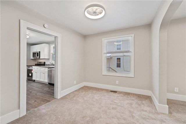 unfurnished room featuring light carpet and sink