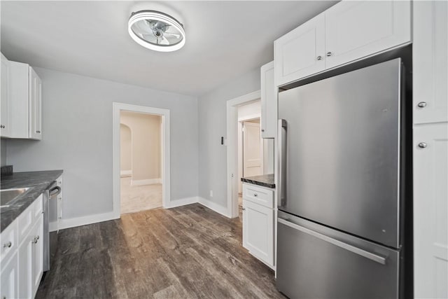 kitchen featuring dark hardwood / wood-style floors, white cabinetry, appliances with stainless steel finishes, and dark stone counters