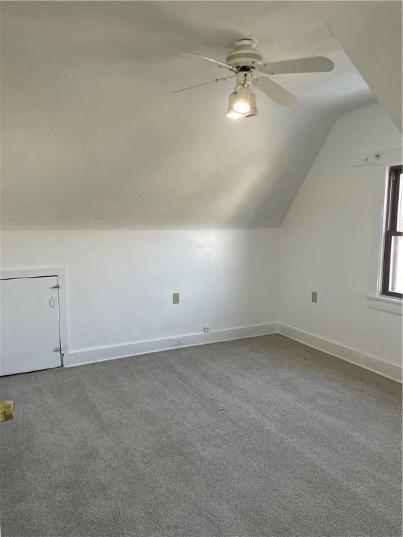 additional living space with carpet flooring, ceiling fan, and lofted ceiling