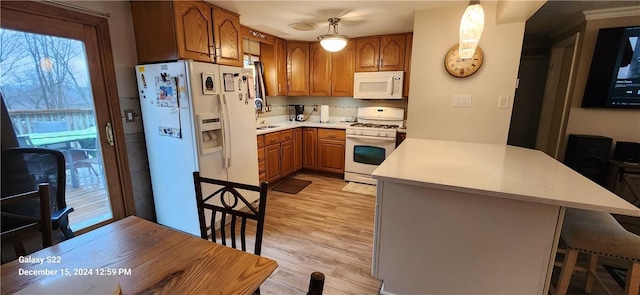 kitchen with tasteful backsplash, kitchen peninsula, pendant lighting, light hardwood / wood-style floors, and white appliances