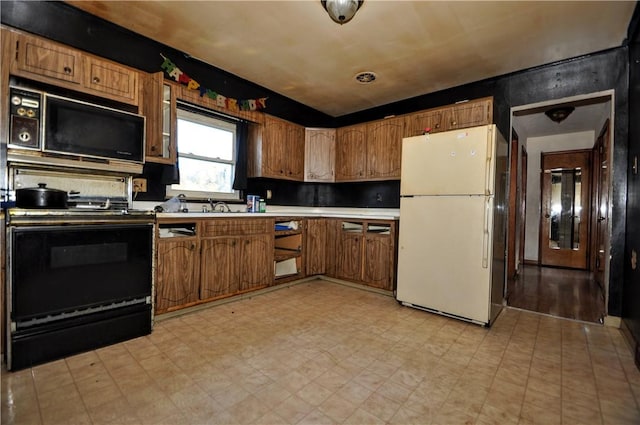 kitchen with black microwave, sink, electric range, and white refrigerator