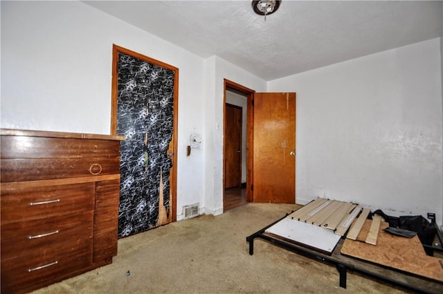 bedroom with light colored carpet and a textured ceiling