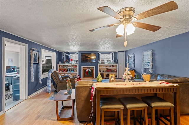 living room with ceiling fan, wood-type flooring, and a textured ceiling