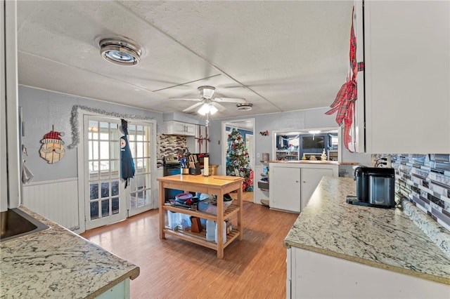 kitchen featuring white cabinets, ceiling fan, light hardwood / wood-style floors, and tasteful backsplash