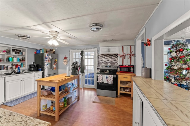 kitchen with sink, light hardwood / wood-style flooring, decorative backsplash, white cabinets, and appliances with stainless steel finishes