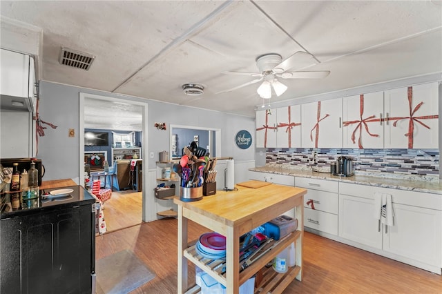 kitchen with decorative backsplash, light stone countertops, ceiling fan, light hardwood / wood-style flooring, and white cabinetry