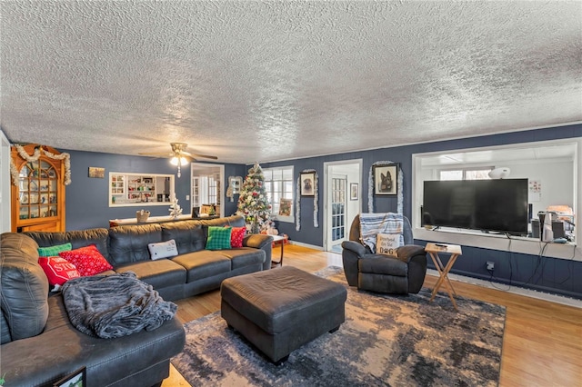 living room featuring ceiling fan, hardwood / wood-style floors, and a textured ceiling