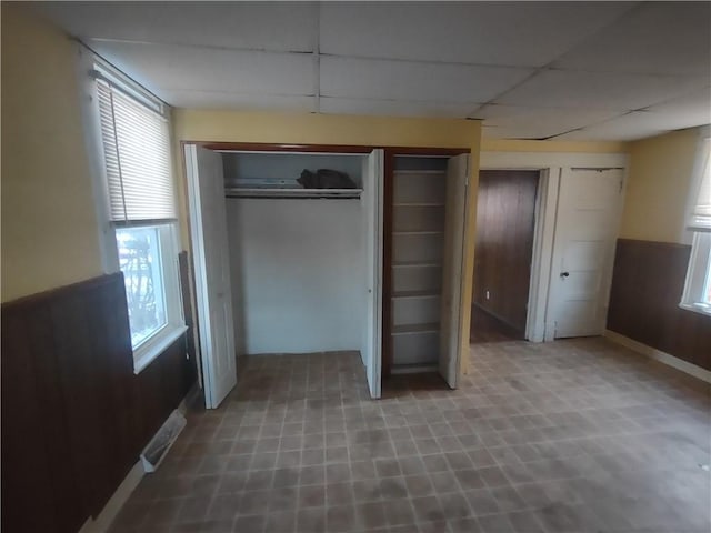 unfurnished bedroom with a drop ceiling and multiple windows