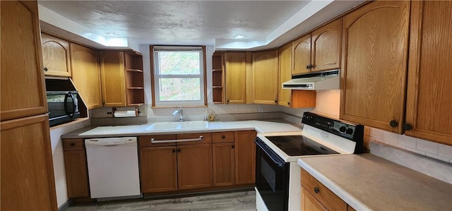 kitchen featuring sink, tasteful backsplash, a textured ceiling, black appliances, and light wood-type flooring