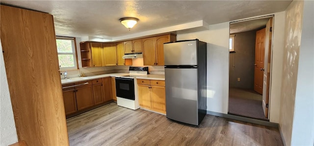 kitchen with white electric range oven, a textured ceiling, stainless steel refrigerator, and light hardwood / wood-style flooring