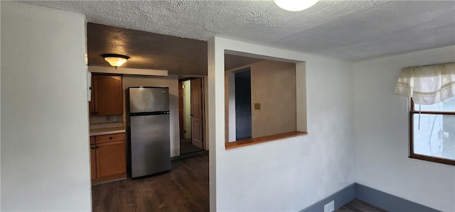 kitchen with dark hardwood / wood-style floors, a textured ceiling, and stainless steel refrigerator