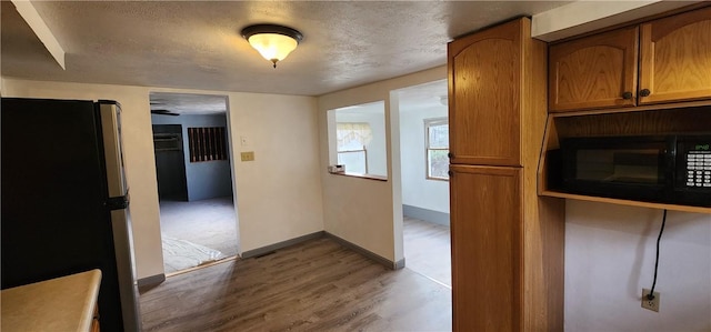 kitchen with stainless steel refrigerator, light hardwood / wood-style flooring, and a textured ceiling