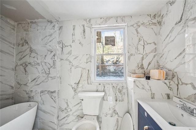 bathroom with vanity, a tub to relax in, toilet, and tile walls