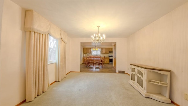 carpeted dining area with an inviting chandelier