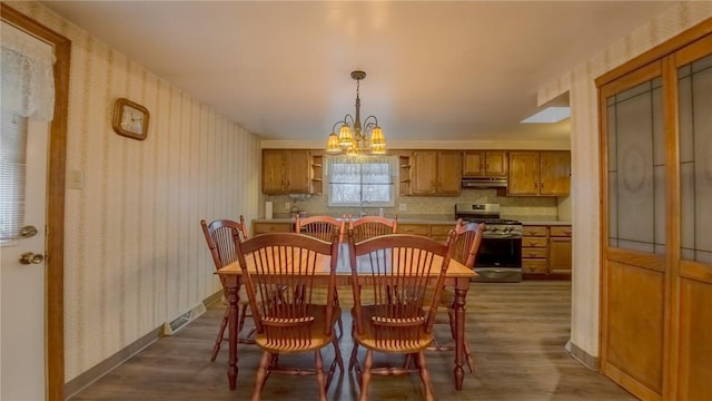 dining area with dark hardwood / wood-style flooring and an inviting chandelier