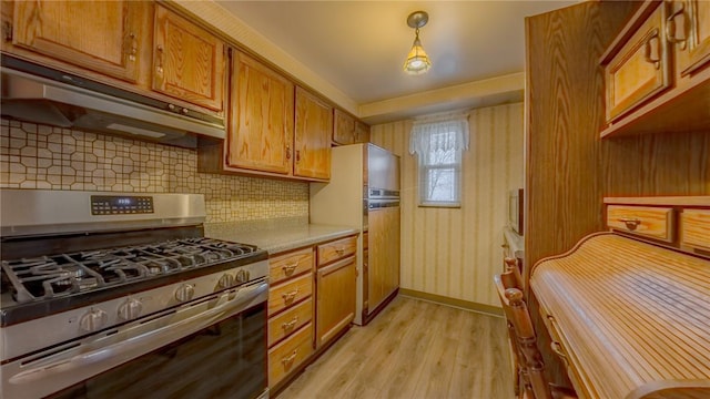 kitchen featuring backsplash, hanging light fixtures, gas range, light hardwood / wood-style floors, and white fridge