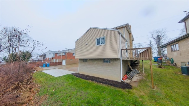 back of house featuring a lawn, a patio, a wooden deck, and central AC