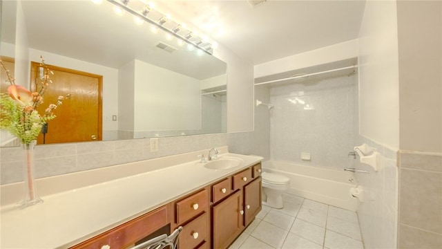 full bathroom featuring vanity, tile patterned flooring, tiled shower / bath combo, toilet, and tile walls