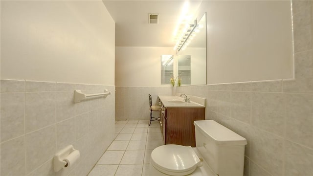 bathroom featuring tile patterned flooring, toilet, and tile walls