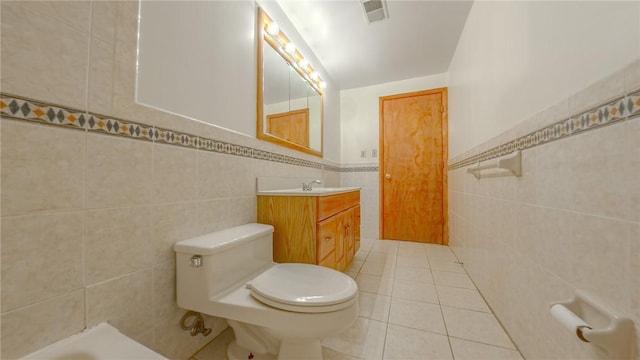 bathroom featuring tile patterned floors, vanity, tile walls, and toilet