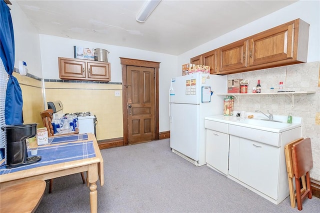 kitchen featuring sink, white fridge, and light colored carpet