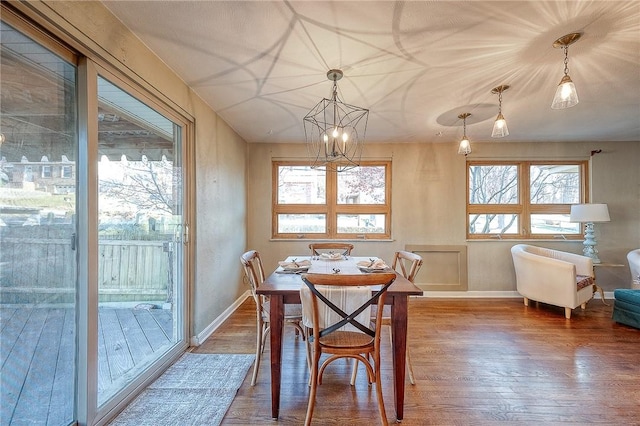 dining area featuring a healthy amount of sunlight, wood-type flooring, and a chandelier