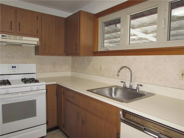 kitchen featuring white appliances, sink, and exhaust hood