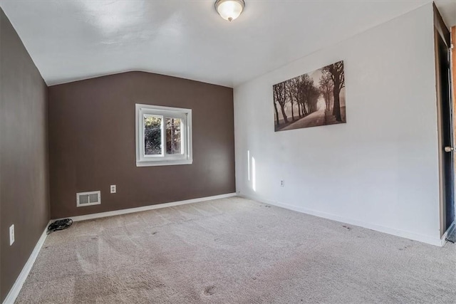 carpeted empty room featuring vaulted ceiling