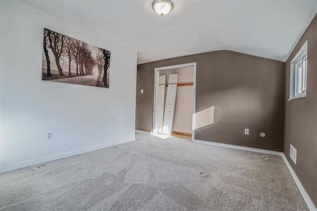 carpeted empty room with lofted ceiling