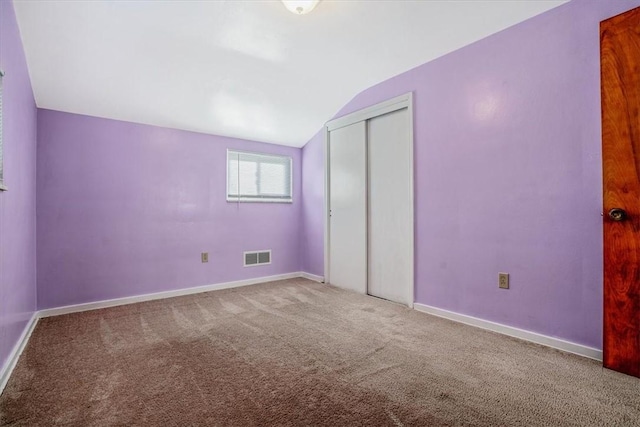 unfurnished bedroom with carpet, a closet, and lofted ceiling