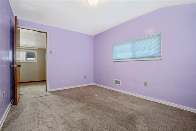 carpeted empty room with vaulted ceiling