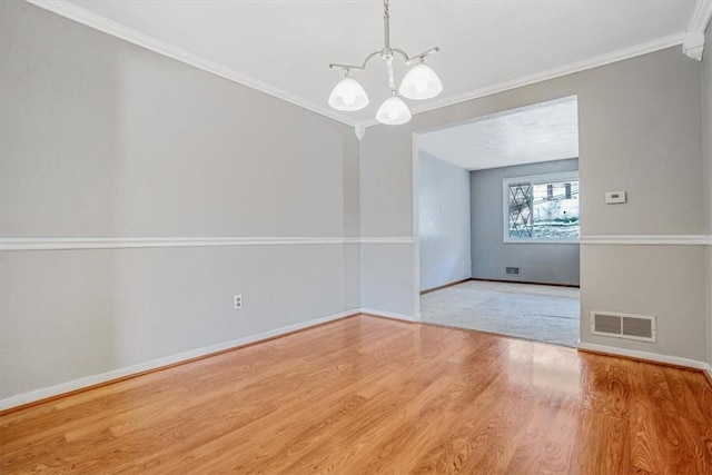 empty room with an inviting chandelier, light hardwood / wood-style flooring, and crown molding