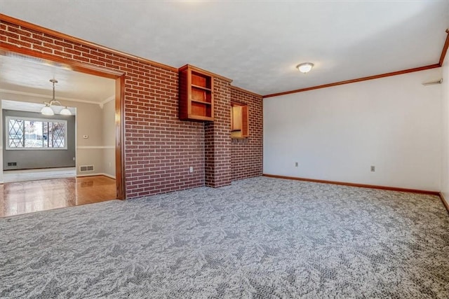 unfurnished living room featuring carpet flooring, crown molding, and brick wall