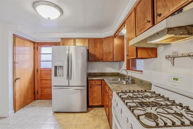 kitchen featuring light tile patterned flooring, stainless steel fridge, gas range gas stove, and sink